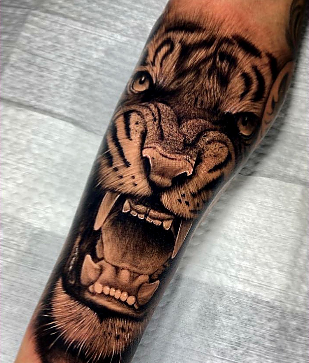 Tatuaje realista de tigre rugiendo en el antebrazo
